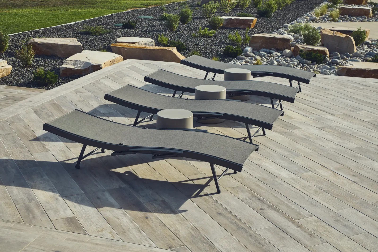 Row of chaise lounges on a wood-look porcelain paver pool deck, Colorado