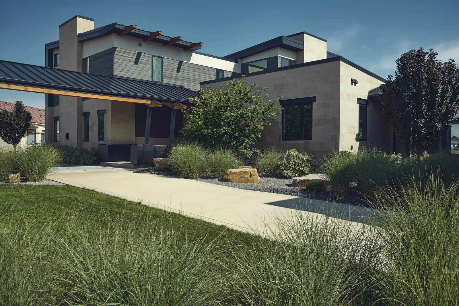Modern home entry with lawn, decomposed granite walk, ornamental grasses, and boulder accents, Colorado