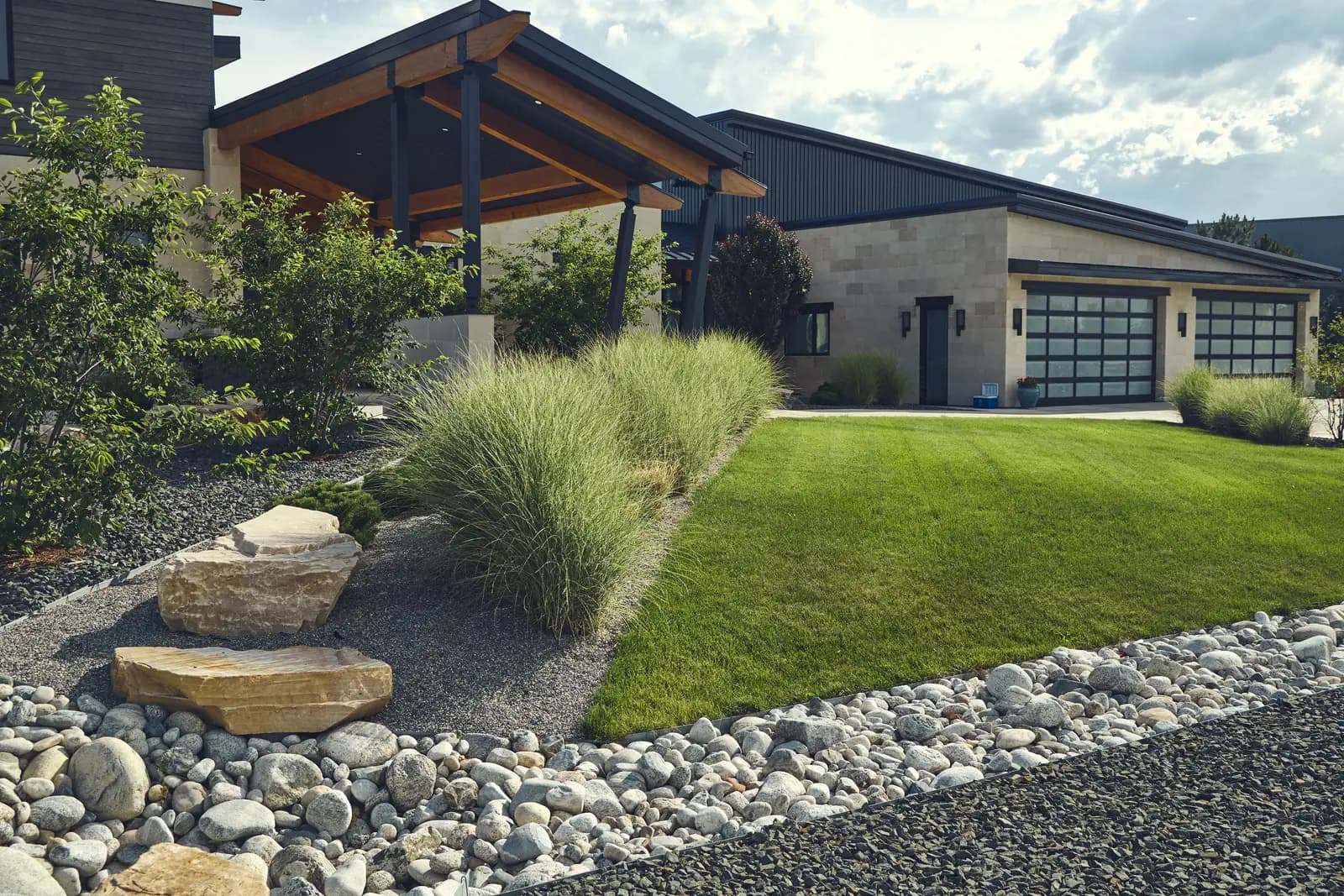 Timber-accented covered entry with lawn, ornamental grasses, and boulder landscape, Colorado