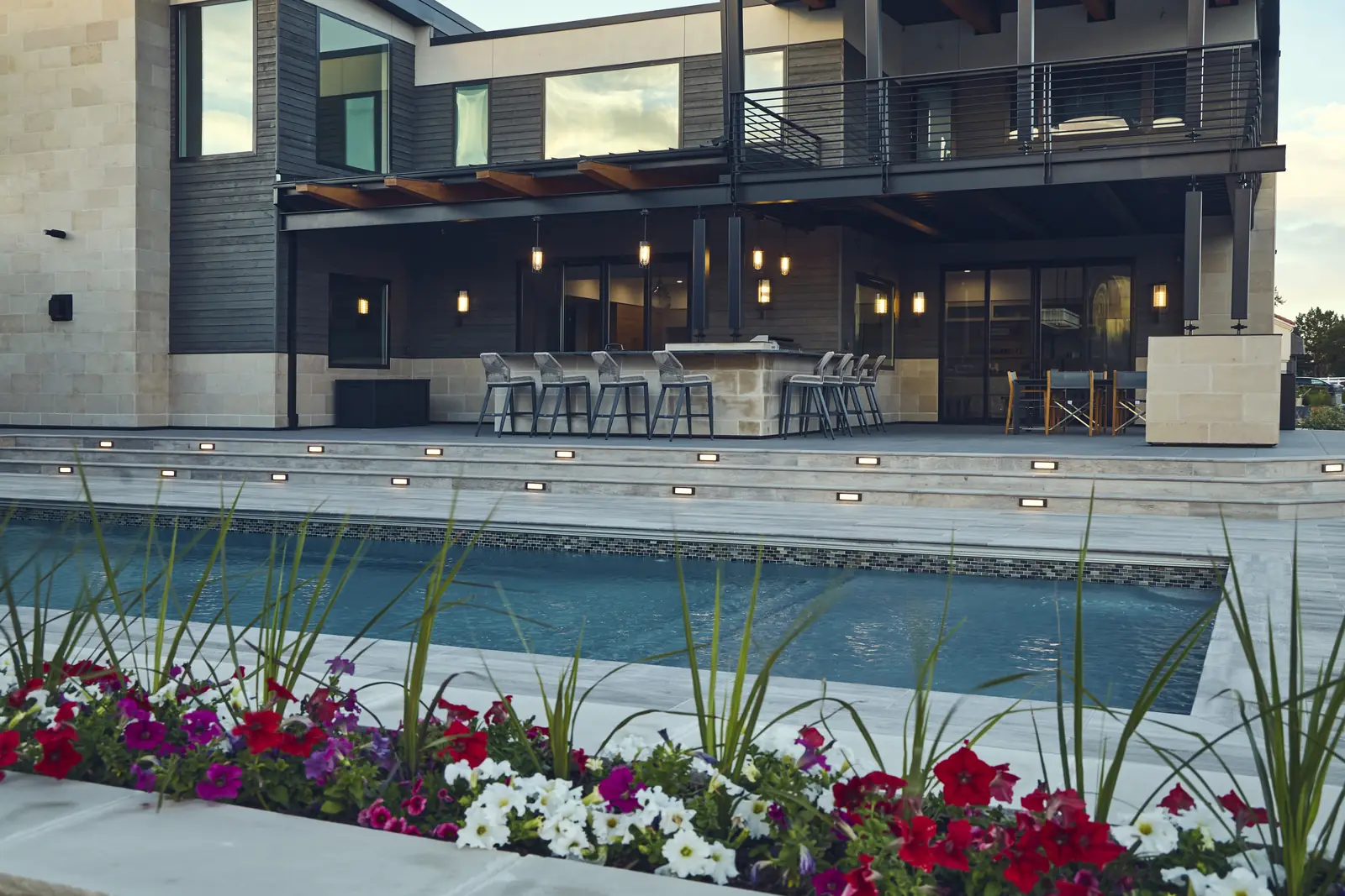 Pool with raised petunia planter and outdoor bar seating at a modern Colorado home