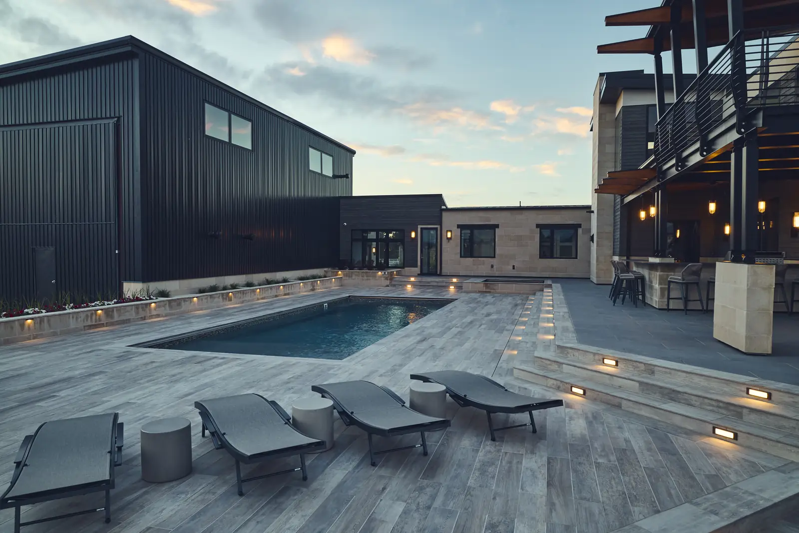 Pool with chaise lounges and recessed step lighting glowing at dusk, Colorado