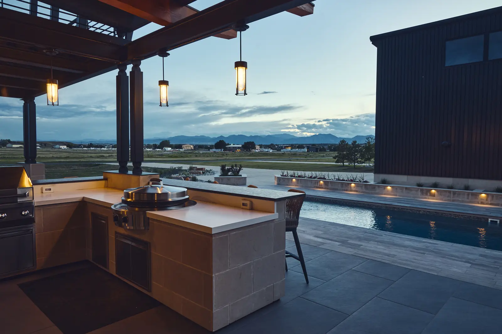 Outdoor kitchen with built-in grill overlooking the pool and prairie sunset, Colorado